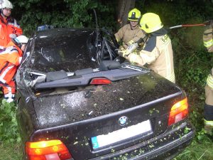 Feuerwehrleute schneiden am C-Holm mit der hydraulischen Schere