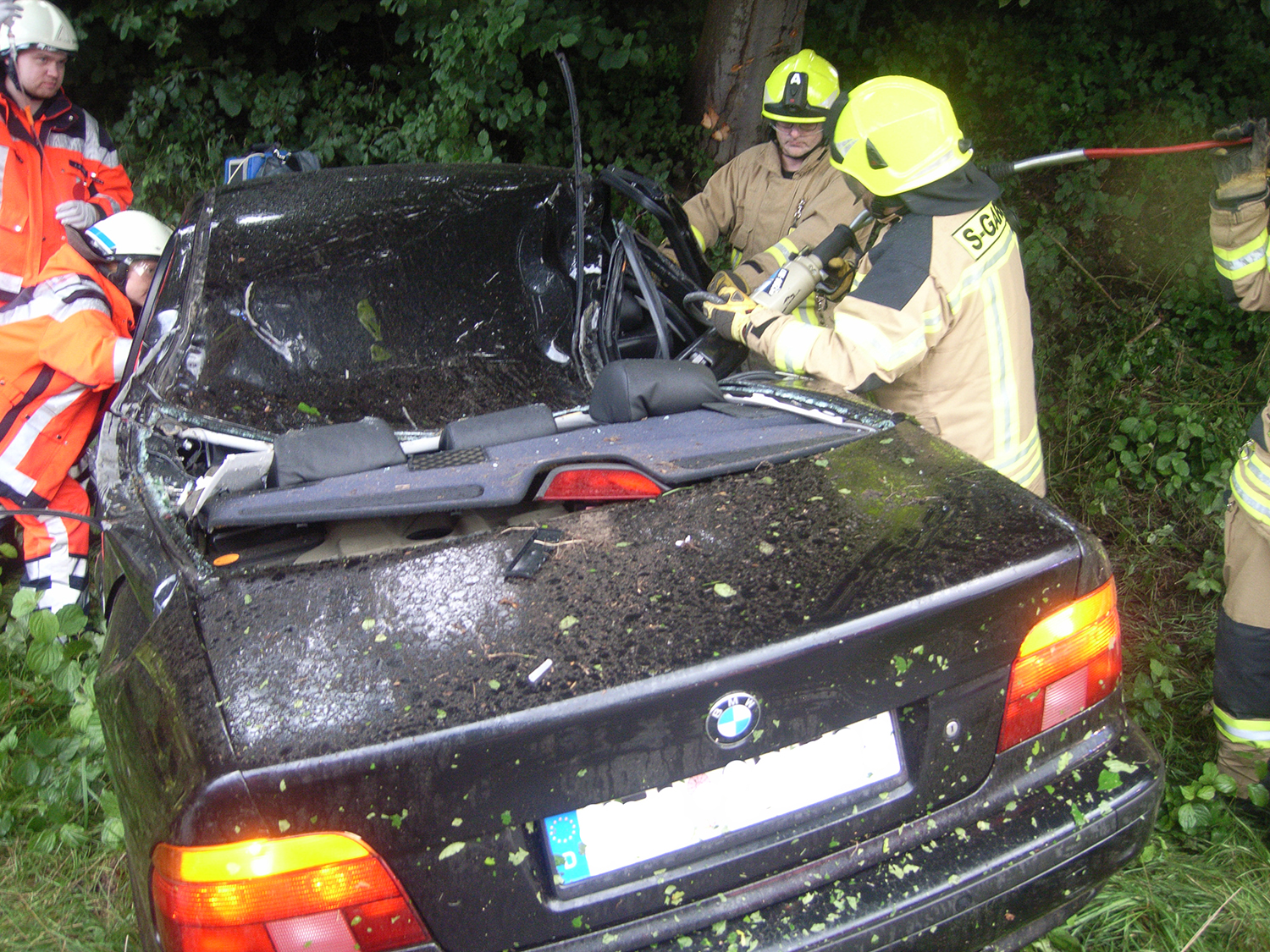 Feuerwehrleute schneiden am C-Holm mit der hydraulischen Schere