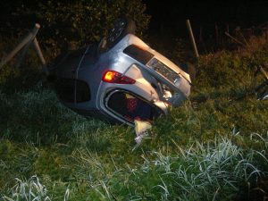 Der Kleinwagen liegt überschlagen vor dem Zaun