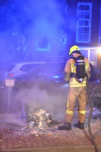 Die Reste einer brennenden Mülltonne werden abgelöscht