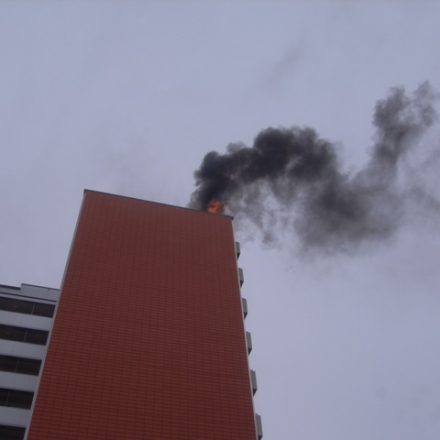 Flammen schlagen aus dem Dachbereich des Hochhauses
