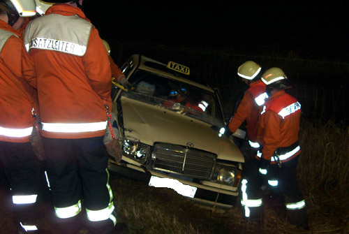 Kurz nach dem Eintreffen der Einsatzkräfte wird die Rettung eingeleitet. Ein Rettungsassistent betreut die Unfallfahrerin im Taxi während von der Feuerwehr die Frontscheibe herausgetrennt wird