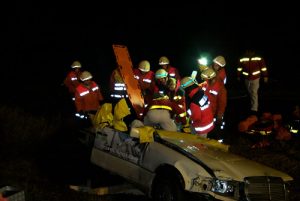 Der Fahrzeugraum ist soweit geöffnet, dass die Fahrerin herausgezogen werden kann. Hierbei unterstützen die Feuerwehrkameraden den Rettungsdienst, da das Terrain nicht immer einen sicheren Stand gewähleistete