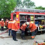 Nach dem Einsatz wird unverzüglich die Einsatzbereitschaft wieder hergestellt. Im Hintergrund spielen die Kinder des Kindergartens, die alle unverletzt von den Erzieherinnen evakuiert worden sind