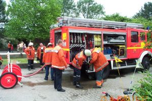 Nach dem Einsatz wird unverzüglich die Einsatzbereitschaft wieder hergestellt. Im Hintergrund spielen die Kinder des Kindergartens, die alle unverletzt von den Erzieherinnen evakuiert worden sind