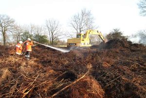 Ein Bagger wurde angefordert und per Tieflader an den Hunnenbarg gebracht. Mit Treckern hätte das auseinander Reißen des Haufens zu lange gedauert