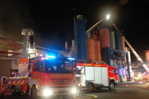 Im Hintergrund die Brandbekämpfung über die Pinneberger Drehleiter, im Vordergrund wird der Teleskopmast aus Elmshorn für den Einsatz vorbereitet