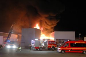 Die Halstenbeker Drehleiter ist zum Schutz der Lagerhalle links sowie zur Brandbekämpfung eingesetzt