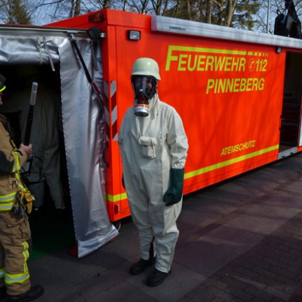 Kamerad vor dem Abrollbehälter Atemschutz/Strahlenschutz in Schutzbekleidung mit den erforderlichen Nachweisgeräten