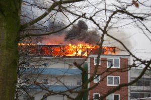 Blick von der Rückseite des Gebäudes, das Dachgeschoß steht im Vollbrand.