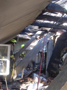 Gegen Absturz gesichert, durchsuchen Feuerwehrleute mit den Kripo-Beamten den Brandschutt