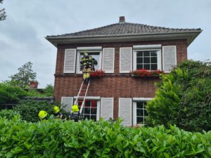 Das Fenster im Obergeschoss wird durch einen Atemschutzträger geöffnet.